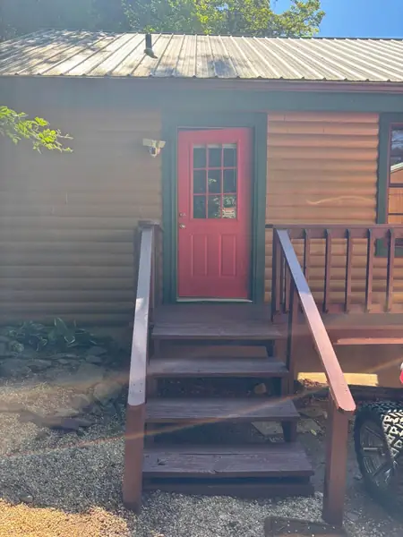 Stained entry steps and handrails leading to a red front door