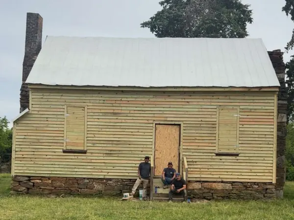 ADA Design and Build crew in front of a farmhouse they restored with new siding, door and steps