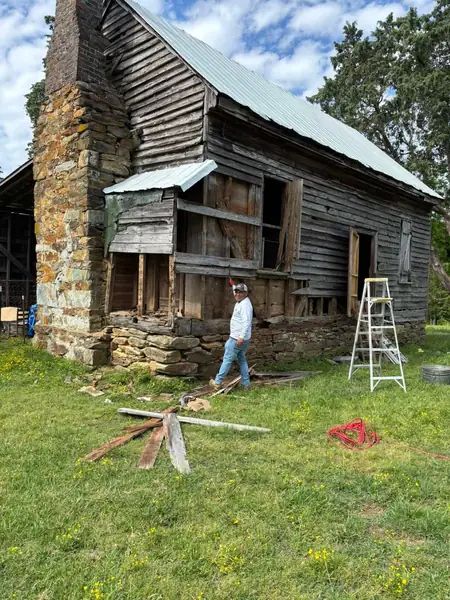 Old farmhouse with rotted siding being removed before restoration