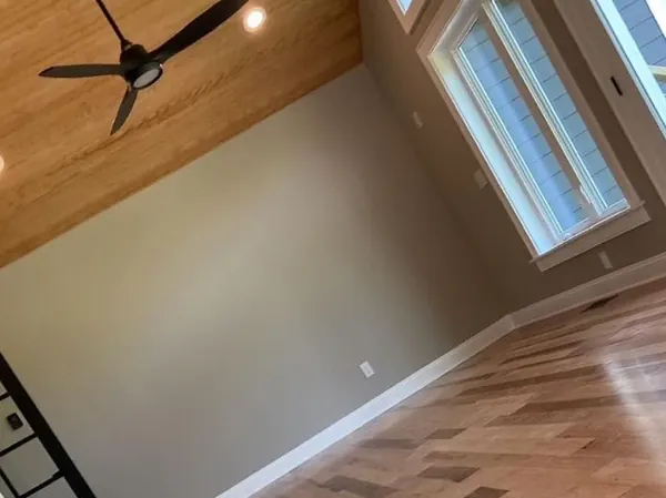 Living room with freshly painted walls and white baseboards over herringbone hardwood floors