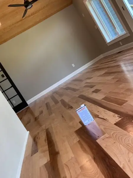 Room with freshly painted walls and white trim over a herringbone hardwood floor
